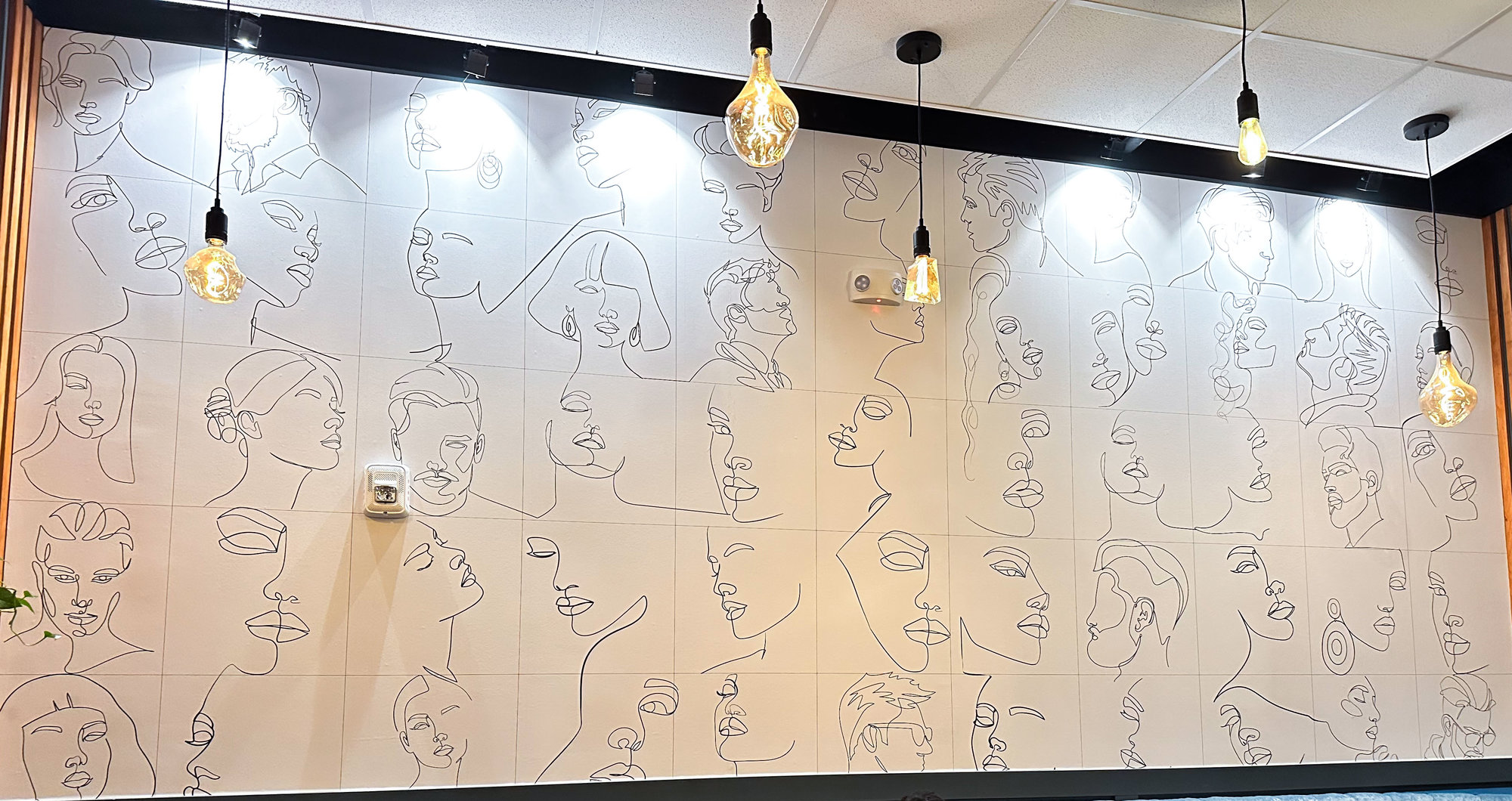 white wall with single line mural of faces